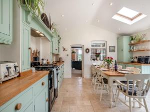 uma cozinha com armários verdes e uma mesa com cadeiras em Bells Cottage em Wrentham