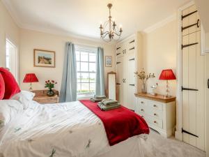 um quarto com uma cama com um cobertor vermelho em Bells Cottage em Wrentham