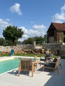 a patio with two chairs and a table and a pool at La ferme de la truffe chambres d hôtes in Cuzance