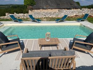 a pool with chairs and a table and a vase at La ferme de la truffe chambres d hôtes in Cuzance