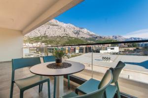 a table and chairs on a balcony with a view of a mountain at Lux Ella Apartment in Makarska