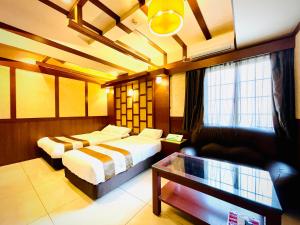 大阪市にある嵐 Hotel Arashi 心斎橋店のベッド2台とソファが備わるホテルルームです。