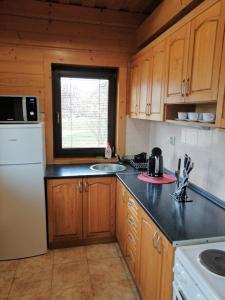 a kitchen with wooden cabinets and a white refrigerator at Chaty Rybárska Osada in Liptovská Sielnica