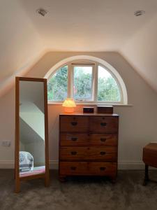a bedroom with a window and a dresser with a mirror at Peaceful cottage with private garden in Hailsham