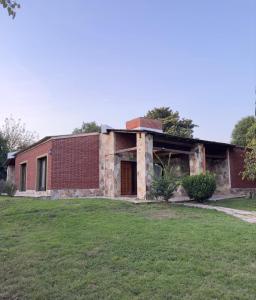 an old brick building with a grass field in front of it at Casa en Barrio el Golf in Alta Gracia