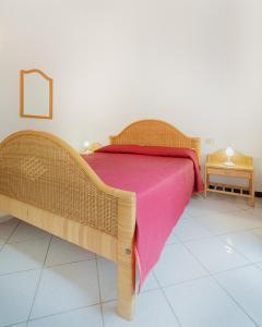 ein Schlafzimmer mit einem Holzbett mit einer rosa Decke in der Unterkunft AMBRA Holiday Rooms in San Teodoro