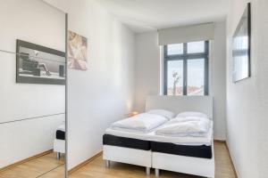a white bedroom with a bed and a mirror at SeaView mit Badesteg in Malchow