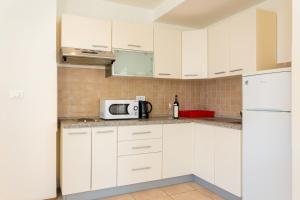 a kitchen with a stove, microwave, sink and cabinets at Old City Apartments in Dubrovnik