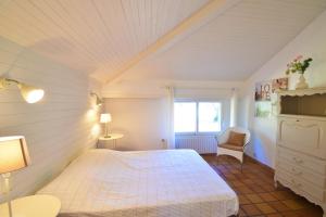 a bedroom with a white bed and a chair at Tiokers - Hossegor - Confortable villa sur terrain clos idéalement située entre lac et Océan et à 1200m du centre ville in Soorts-Hossegor