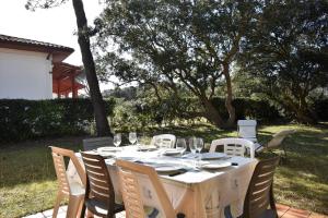 a table with chairs and wine glasses on a patio at Tiokers - Hossegor - Confortable villa sur terrain clos idéalement située entre lac et Océan et à 1200m du centre ville in Soorts-Hossegor