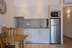 a kitchen with white cabinets and a stainless steel refrigerator at Quinta dos Poetas Nature Hotel & Apartments in Olhão
