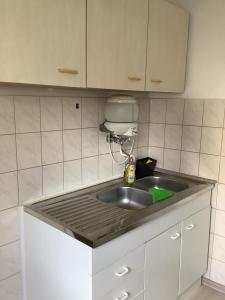 una cocina con fregadero de acero inoxidable y armarios blancos en City-Wohnung 12a, en Brühl
