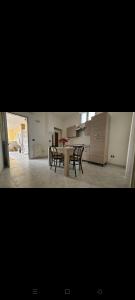 una mesa y sillas en una habitación con cocina en La Curte, en Melendugno
