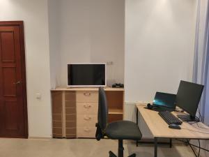 una oficina con escritorio con 2 ordenadores portátiles y TV en Vacation House en Truskavets