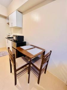 uma cozinha com uma mesa de madeira e cadeiras num quarto em I Best Value Studio em Iloilo