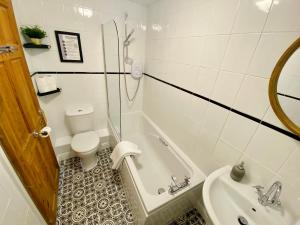 a bathroom with a toilet and a tub and a sink at Liberty House in Weston-super-Mare