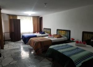 リオバンバにあるHostería la Gaviotaのベッド3台と窓が備わるホテルルームです。