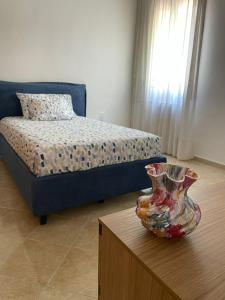 1 dormitorio con 1 cama y un jarrón sobre una mesa en A Casa dei Nonni, en Cavallino-Treporti