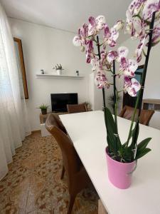 Una mesa blanca con un jarrón rosa con flores. en A Casa dei Nonni, en Cavallino-Treporti