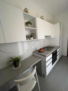 una cocina con armarios blancos y una barra con fruta. en A Casa dei Nonni, en Cavallino-Treporti