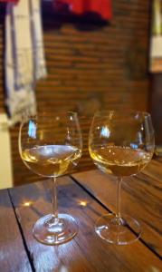 two glasses of white wine sitting on a wooden table at Domaćinska kuća in Arandjelovac