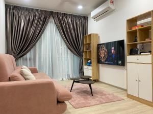 sala de estar con sofá rosa y TV en Meow’s Cozy Place, en Kuching
