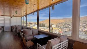 a room with chairs and tables and large windows at Beit Alshabaan Inn in Wadi Musa