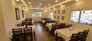 een restaurant met tafels en stoelen met witte tafelkleden bij Beit Alshabaan Inn in Wadi Musa
