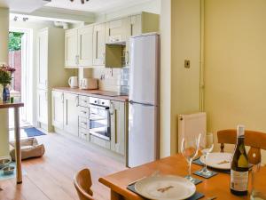 a kitchen with a table and a white refrigerator at Sandy Paws in Gorleston-on-Sea