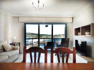 a living room with a table and chairs and a large window at Desconectaengalicia Puerto de Portonovo in Portonovo