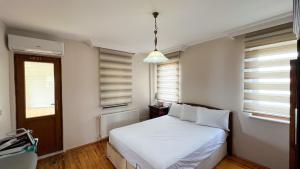 a bedroom with a bed with white sheets and windows at Heaven Garden Villa in Trabzon