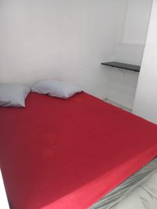 ein Bett mit einer roten Decke darüber in der Unterkunft Hostel Mar da Vila in Praia Grande