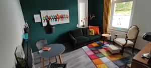 a living room with a green couch and a colorful rug at Villa Kunterbunt, Gemütlichkeit am Waldesrand in Drangstedt