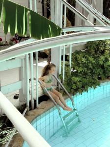 a woman in a bathing suit sitting on a ladder by a swimming pool at Eili Suites in Moshav Ramot