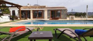 a villa with a pool and two chairs and a table at Casa Rancho Grande in Jávea