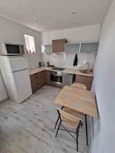 Il comprend une cuisine équipée d'une table en bois et d'un réfrigérateur blanc. dans l'établissement Przytulny apartament + siłownia, à Bytom