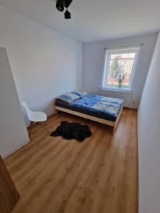 - une chambre avec un lit et une chaise sur du parquet dans l'établissement Przytulny apartament + siłownia, à Bytom