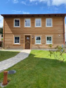 una casa de madera con un césped verde delante de ella en BERGLAGE - Das UrlaubZuhause - Ferienhäuser, en Braunlage