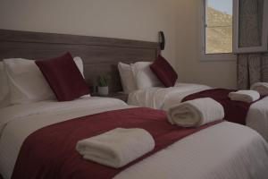 two beds in a hotel room with towels on them at Petra Passion Inn in Taiyiba