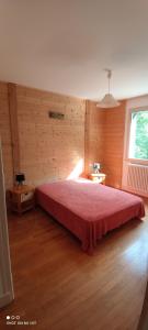 Gîte grande capacité au calme circuit Cascades du Hérisson في Bonlieu: غرفة نوم بسرير احمر في جدار خشبي