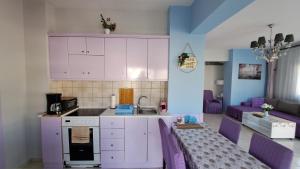 a kitchen with purple cabinets and a living room at Mary's Apartment in Kos