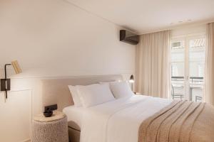 ein Schlafzimmer mit einem großen weißen Bett und einem Fenster in der Unterkunft Doryssa Theorem Hotel in Pythagoreio