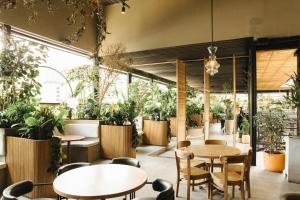 ein Restaurant mit Tischen, Stühlen und Topfpflanzen in der Unterkunft The Art Hotel Medellin in Medellín