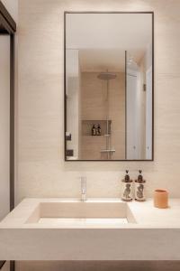 a bathroom with a white sink and a mirror at Doryssa Theorem Hotel in Pythagoreio