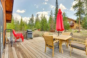 eine Holzterrasse mit Stühlen, einem Tisch und einem roten Regenschirm in der Unterkunft Serene Grand Lake Vacation Rental with Private Deck! in Grand Lake