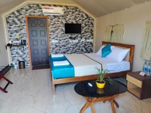 a bedroom with a bed and a tv on a wall at Nature's Deck - River Side Cabana's in Kārwār