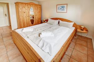 uma grande cama de madeira com lençóis brancos num quarto em fewo1846 - Am Strand - familienfreundliche Wohnung mit 2 Schlafzimmern, Terrasse und Garten em Harrislee