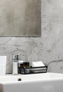 a bathroom sink with a mirror and a basket on it at Plaza Hotel in Loutraki