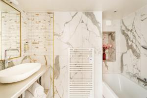 uma casa de banho com uma banheira branca, um lavatório e uma banheira tubermott em Luxury 4 bedroom 4 bathroom Apartment - Louvre em Paris