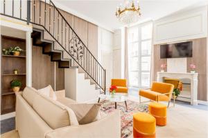 a living room with a staircase and orange chairs at Luxury 4 bedroom 4 bathroom Apartment - Louvre in Paris